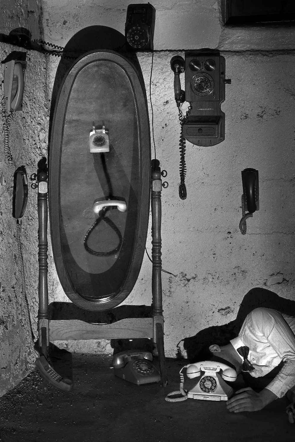 antique telephones and collapsed figure in black and white photo